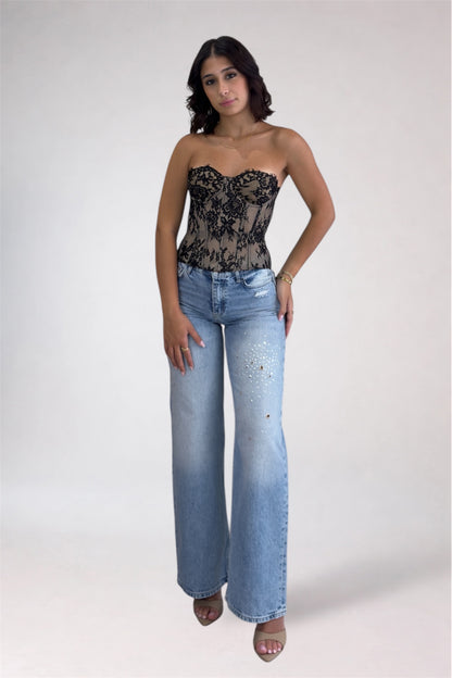 Woman wearing a black lace top and blue jeans on a white background