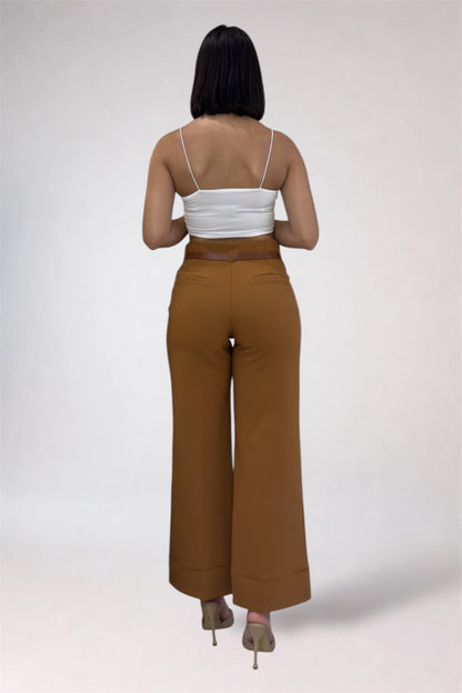 Woman wearing a white top and brown high-waisted pants on a plain background