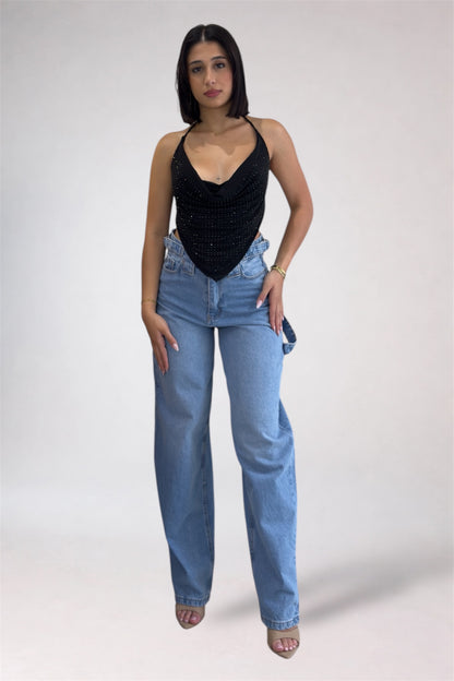 Woman wearing a black top and blue jeans on a white background