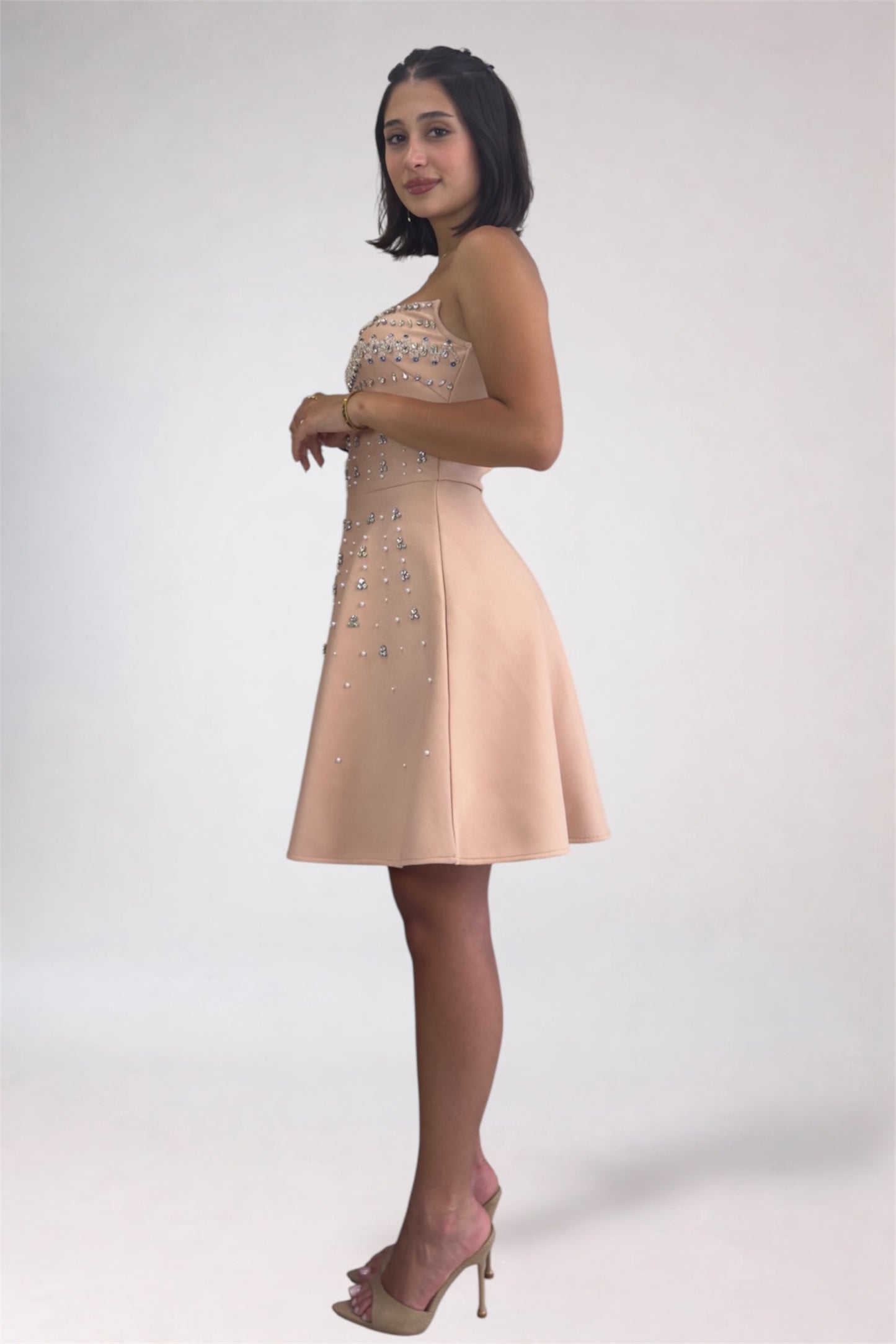 Woman wearing a beige dress with floral embellishments on a white background