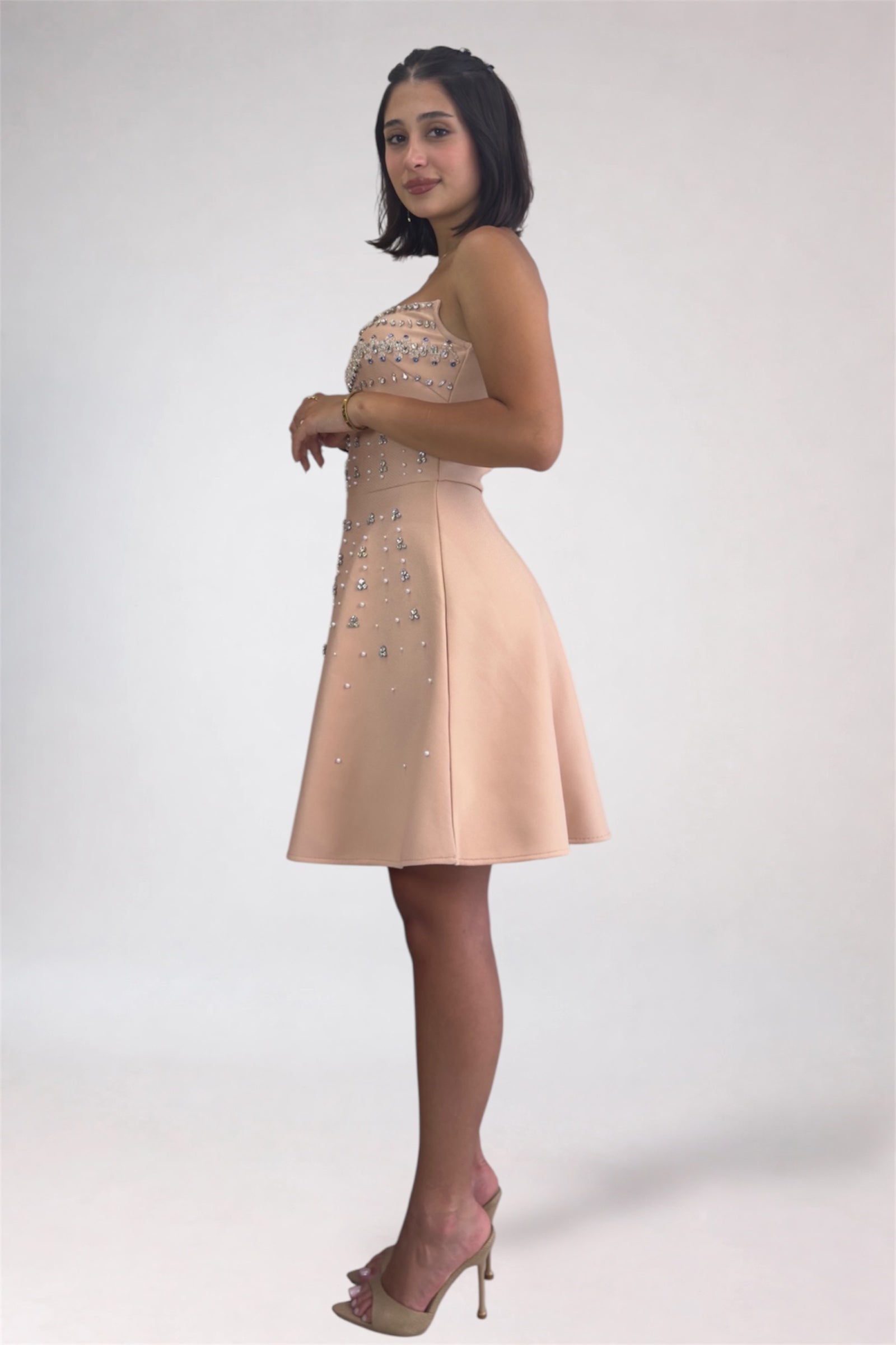 Woman wearing a beige dress with floral embellishments on a white background