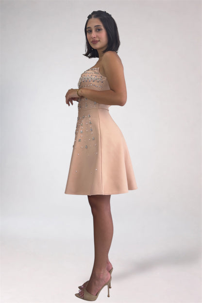 Woman wearing a beige dress with floral embellishments on a white background