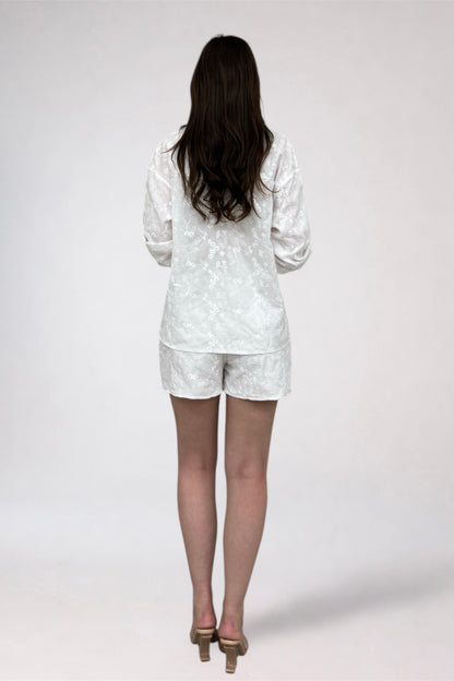 Person wearing a white polka dot outfit on a plain background