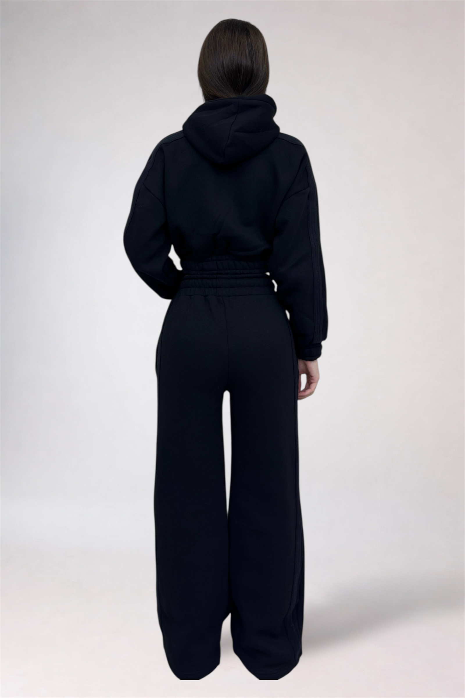 Person wearing a black hoodie and wide-leg pants on a white background