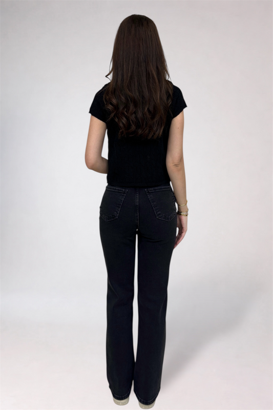 Person wearing black jeans and a black top on a white background