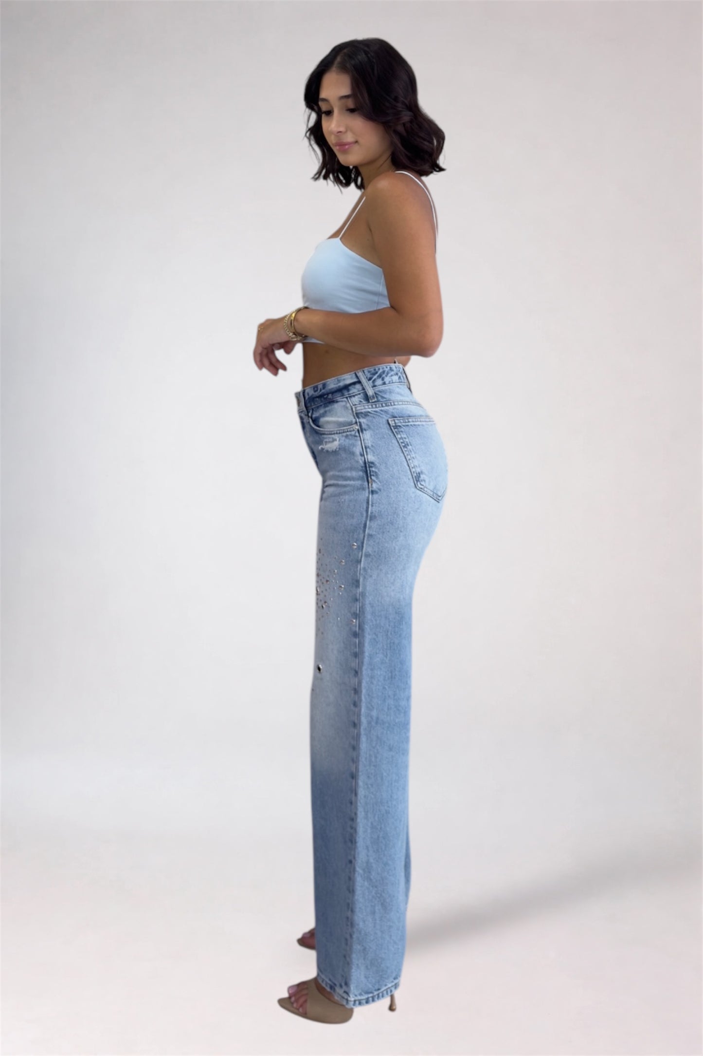 Woman wearing light blue jeans and a matching top on a white background