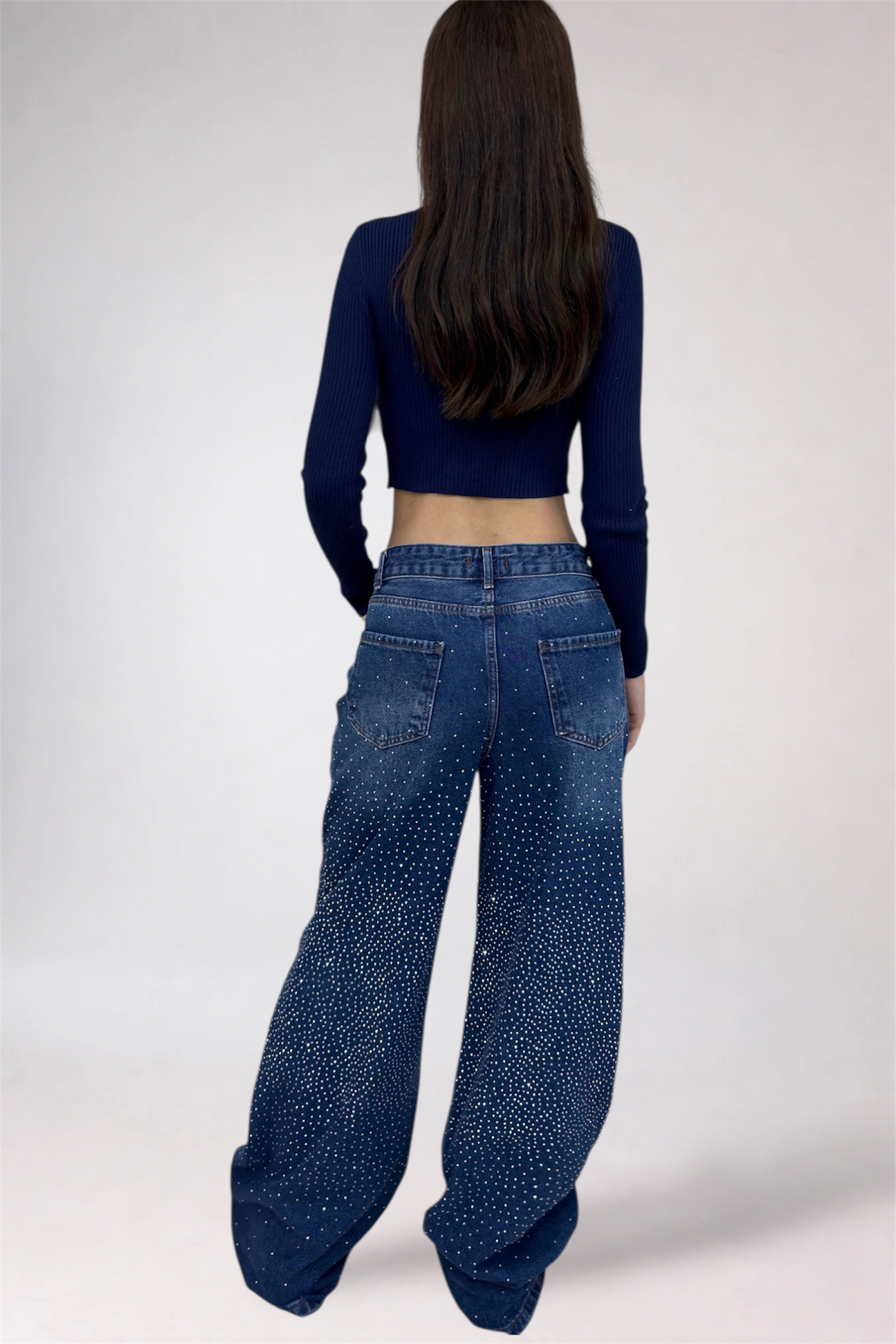 Person wearing blue jeans and a dark top on a white background