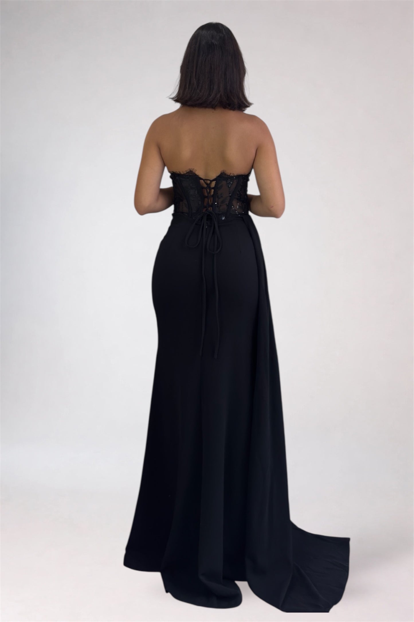 Black strapless gown with lace detailing on a white background