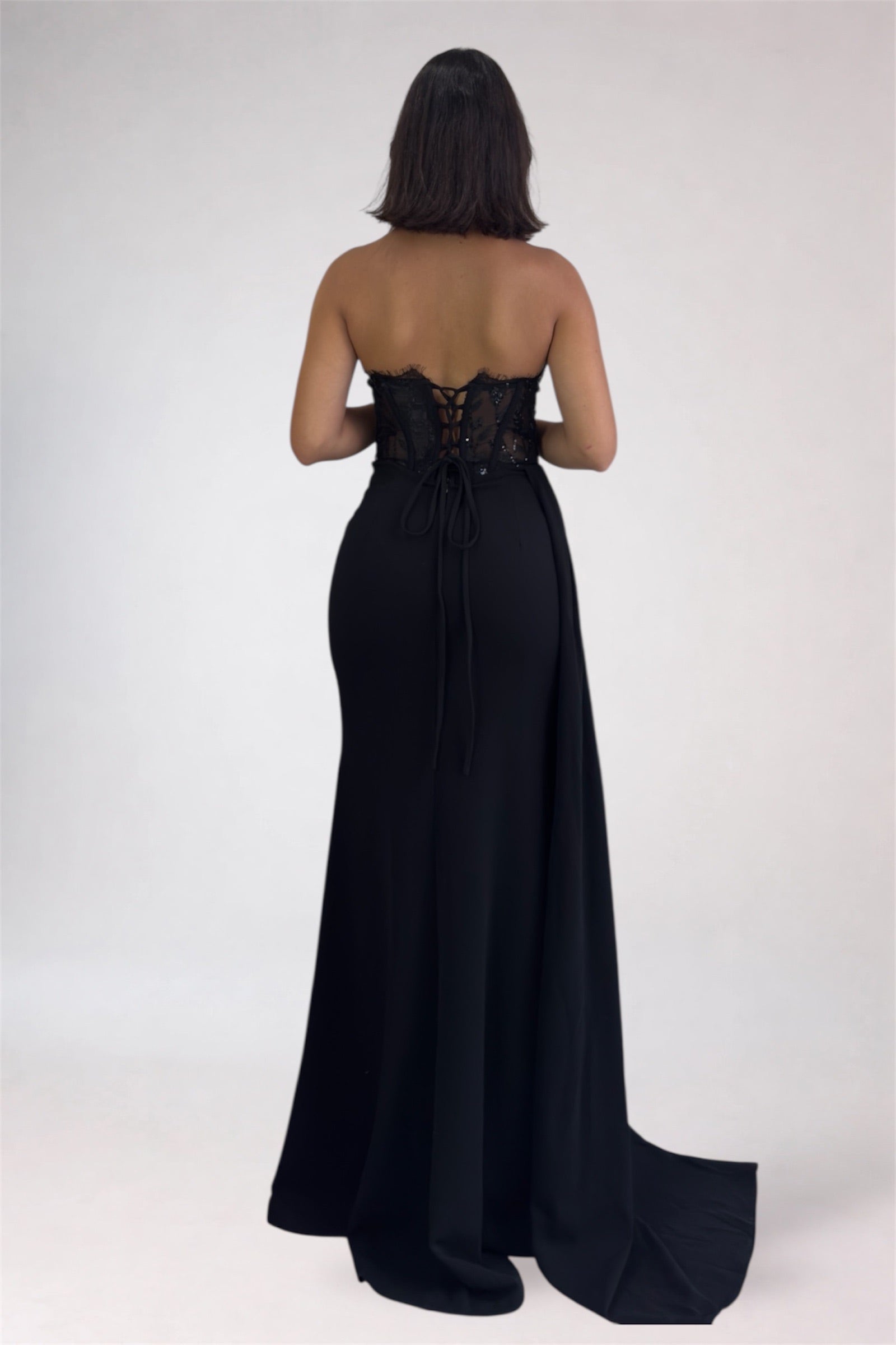 Black strapless gown with lace detailing on a white background