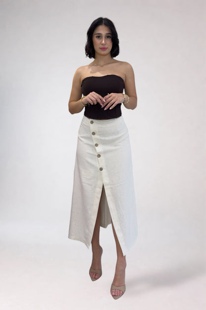 Woman wearing a black strapless top and white button-up skirt on a plain background