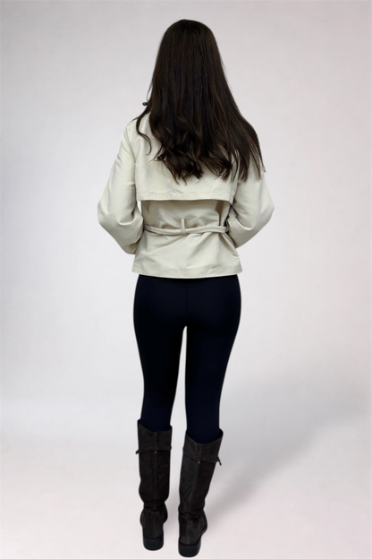 Person wearing a light-colored jacket, dark pants, and black boots on a white background