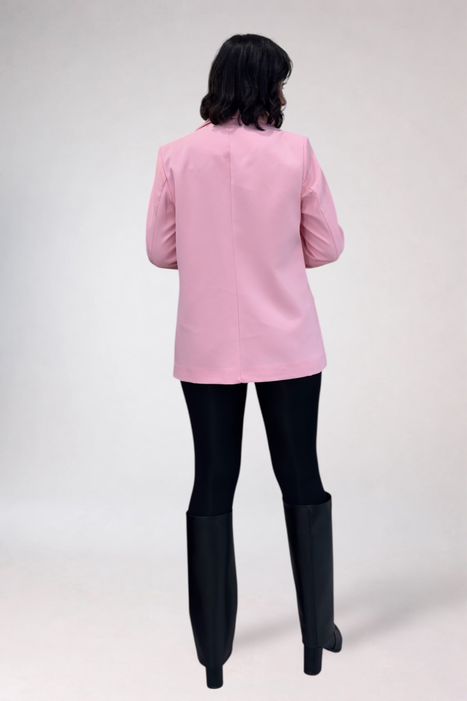 Person wearing a pink blazer and black pants on a white background
