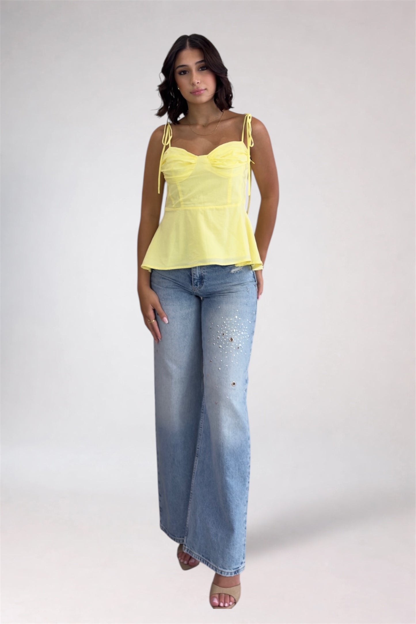 Woman wearing a yellow top and blue jeans on a white background
