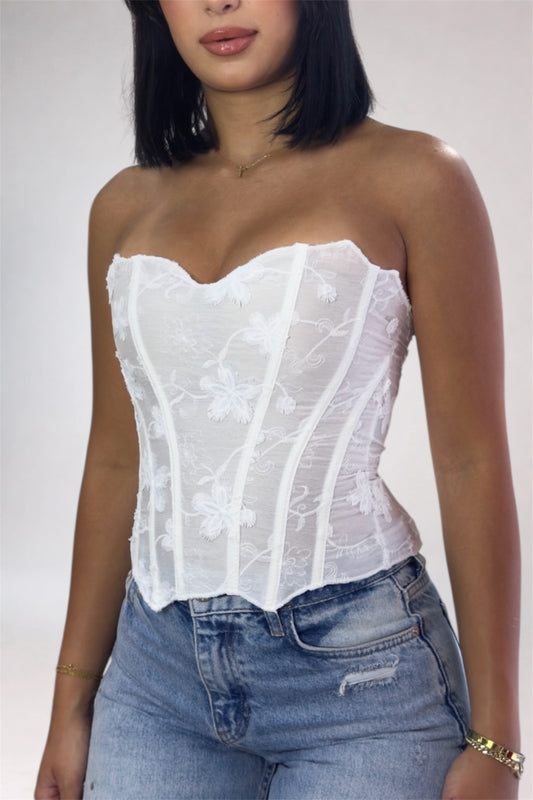Woman wearing a white lace top and blue jeans on a plain background
