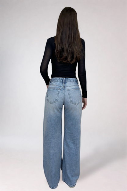 Person wearing blue jeans and a black top on a white background