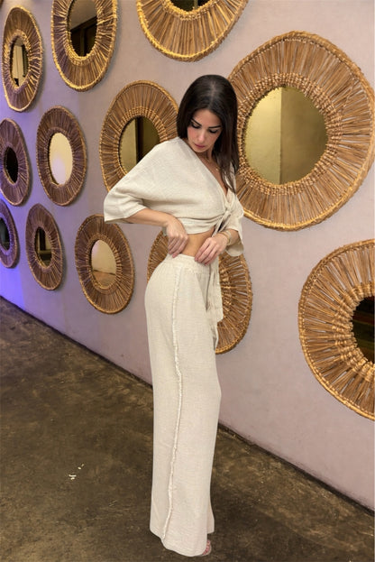 Woman in a white outfit standing in front of decorative wall mirrors.