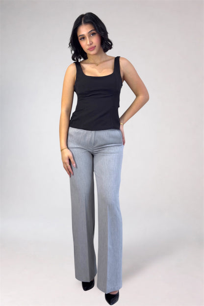 Woman wearing a black tank top and gray pants on a white background