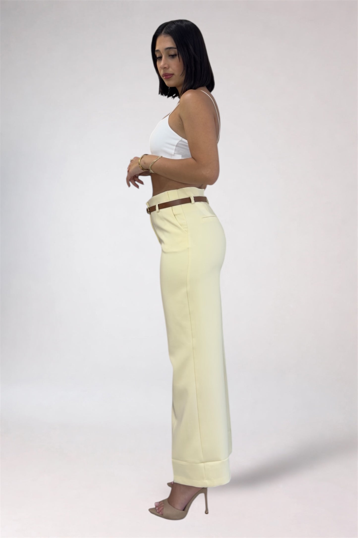 Woman wearing a white top and light yellow pants on a plain background