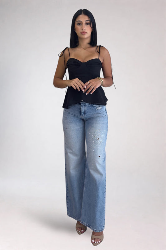 Woman wearing a black top and blue jeans on a white background