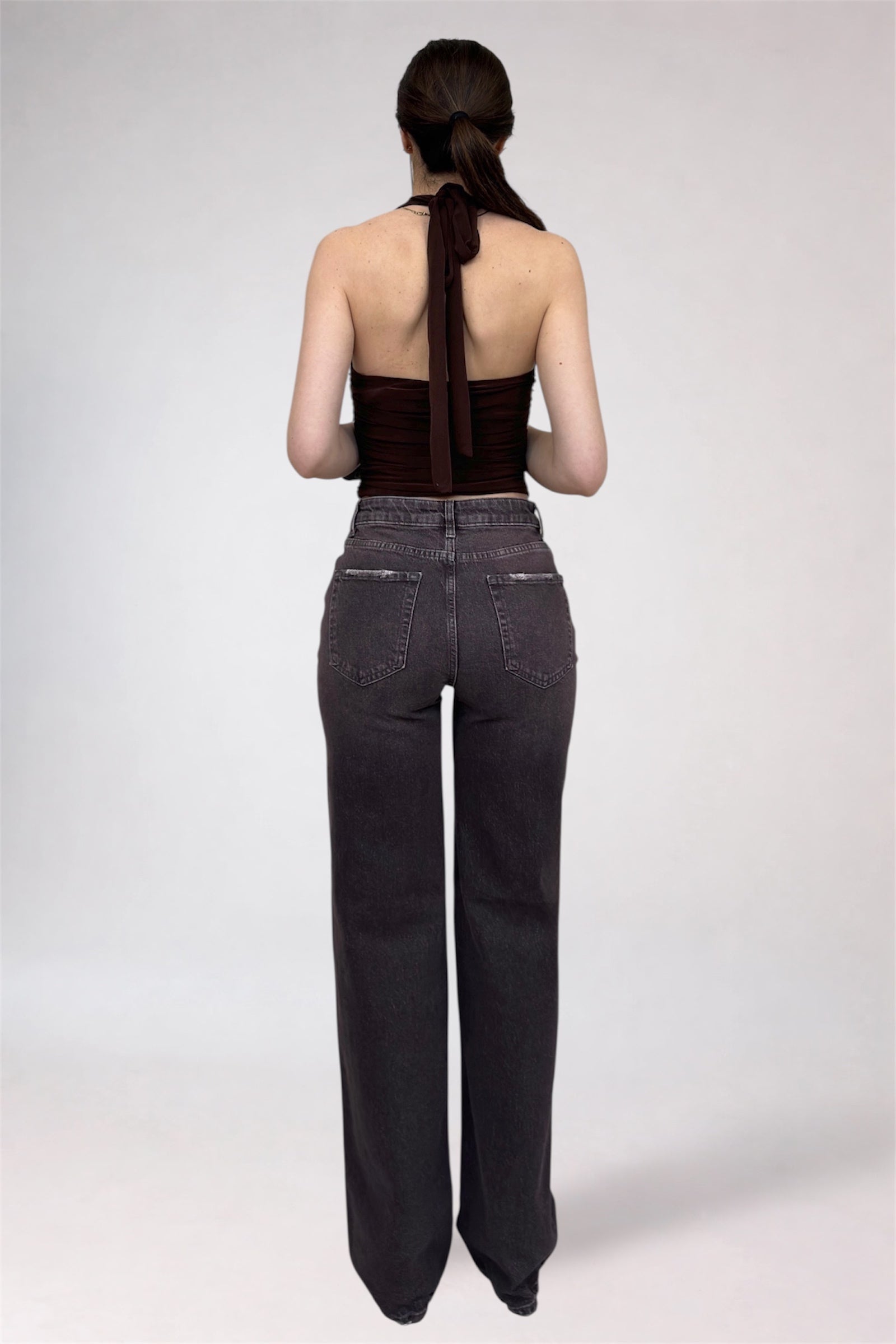 Person wearing dark jeans and a black top on a white background