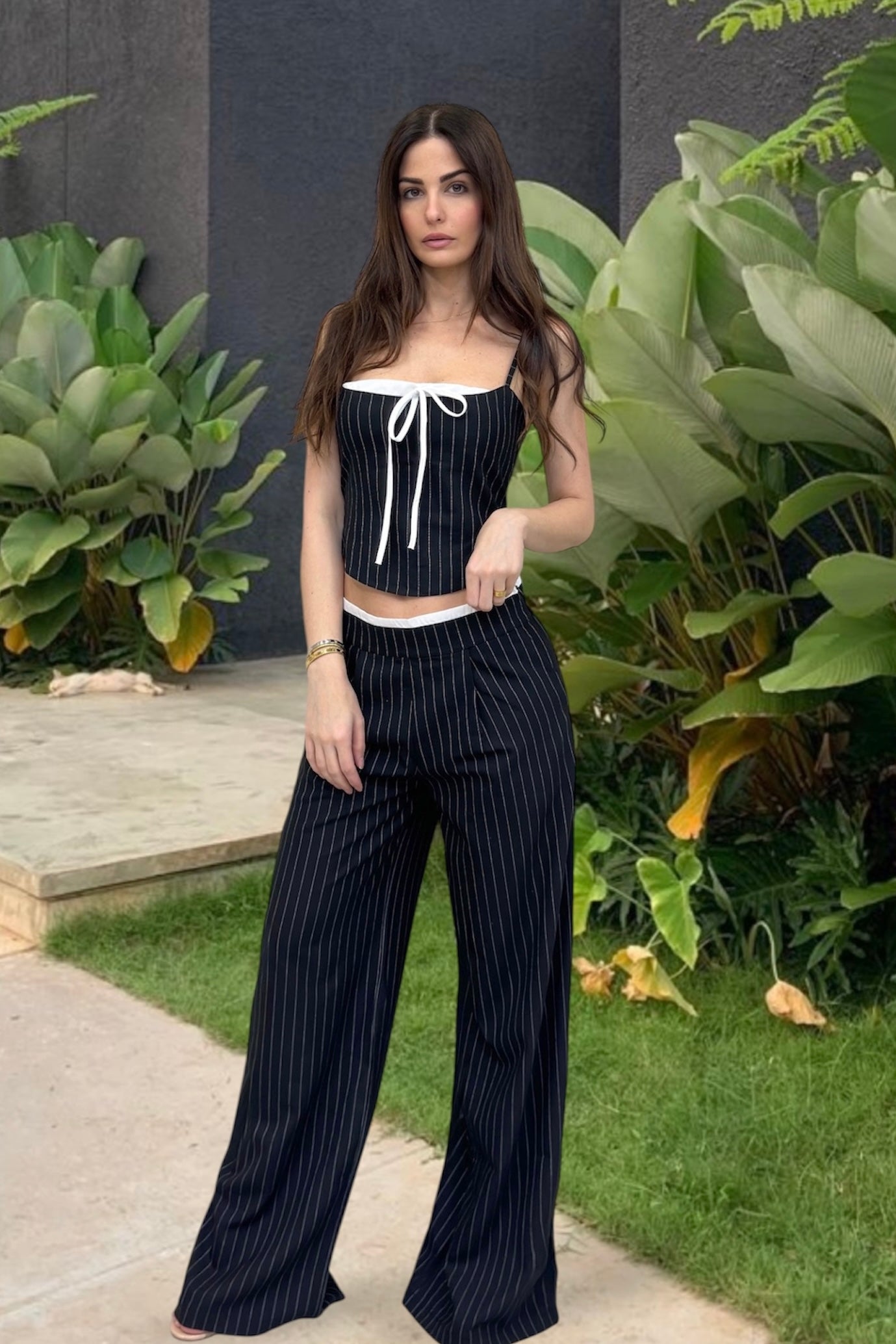 Woman wearing a black pinstripe outfit with a white top in an outdoor setting.