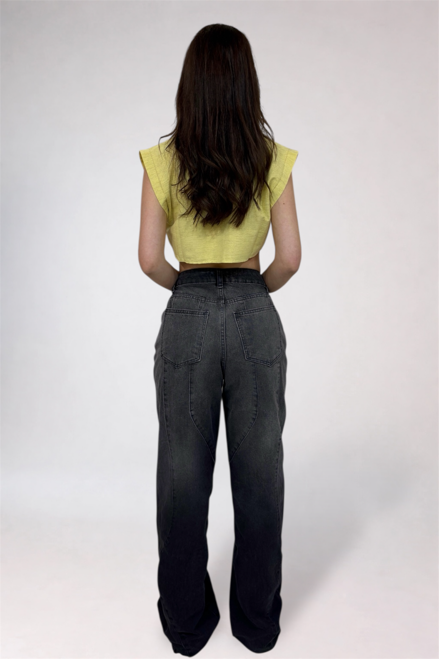 Person wearing a yellow top and dark pants on a white background