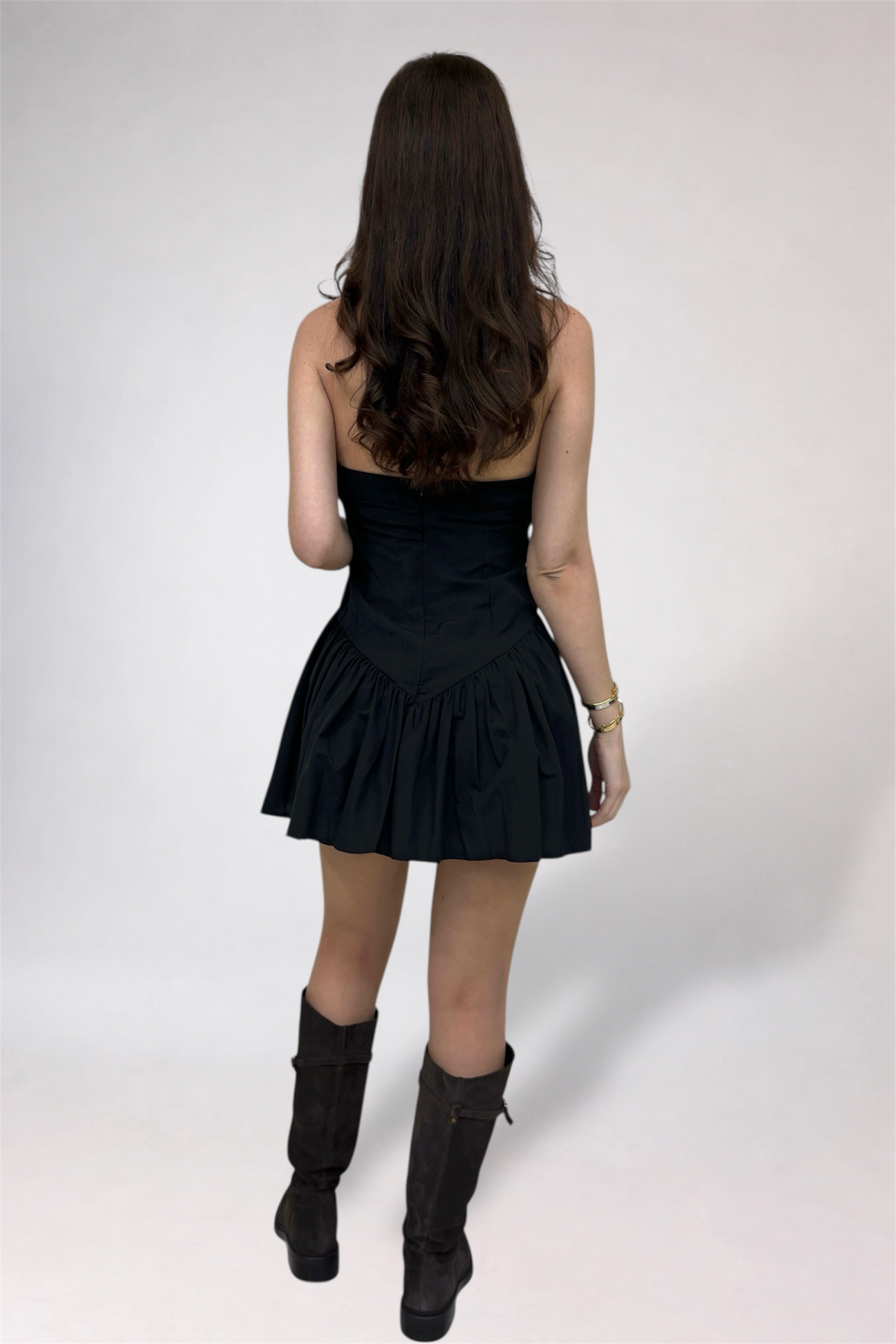 Woman wearing a black dress and black boots on a white background