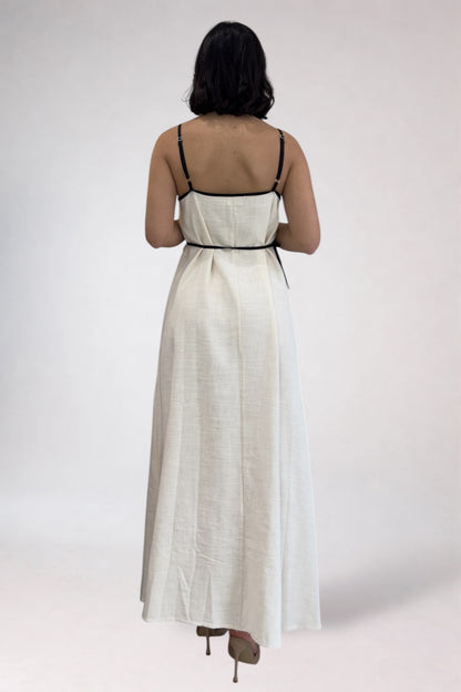 Woman wearing a white dress with black straps on a plain background