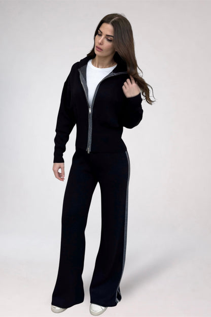 Woman wearing a black tracksuit with a white shirt underneath on a white background