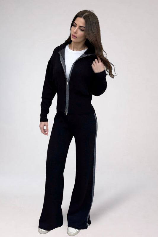 Woman wearing a black tracksuit with a white shirt underneath on a white background