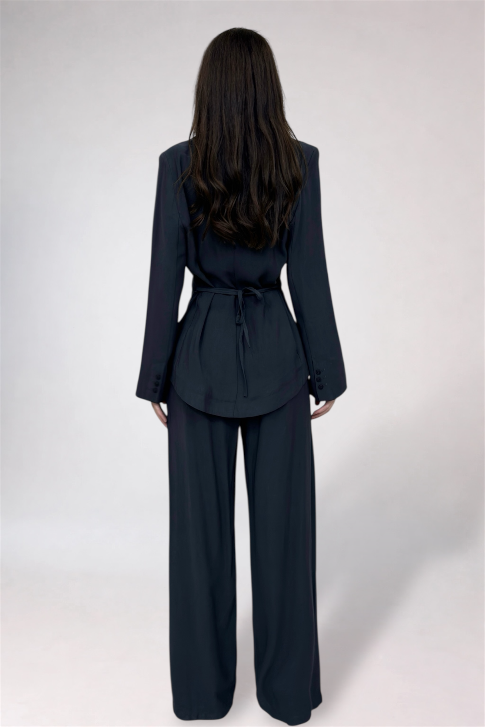 Person wearing a dark blue suit with wide-leg pants on a white background