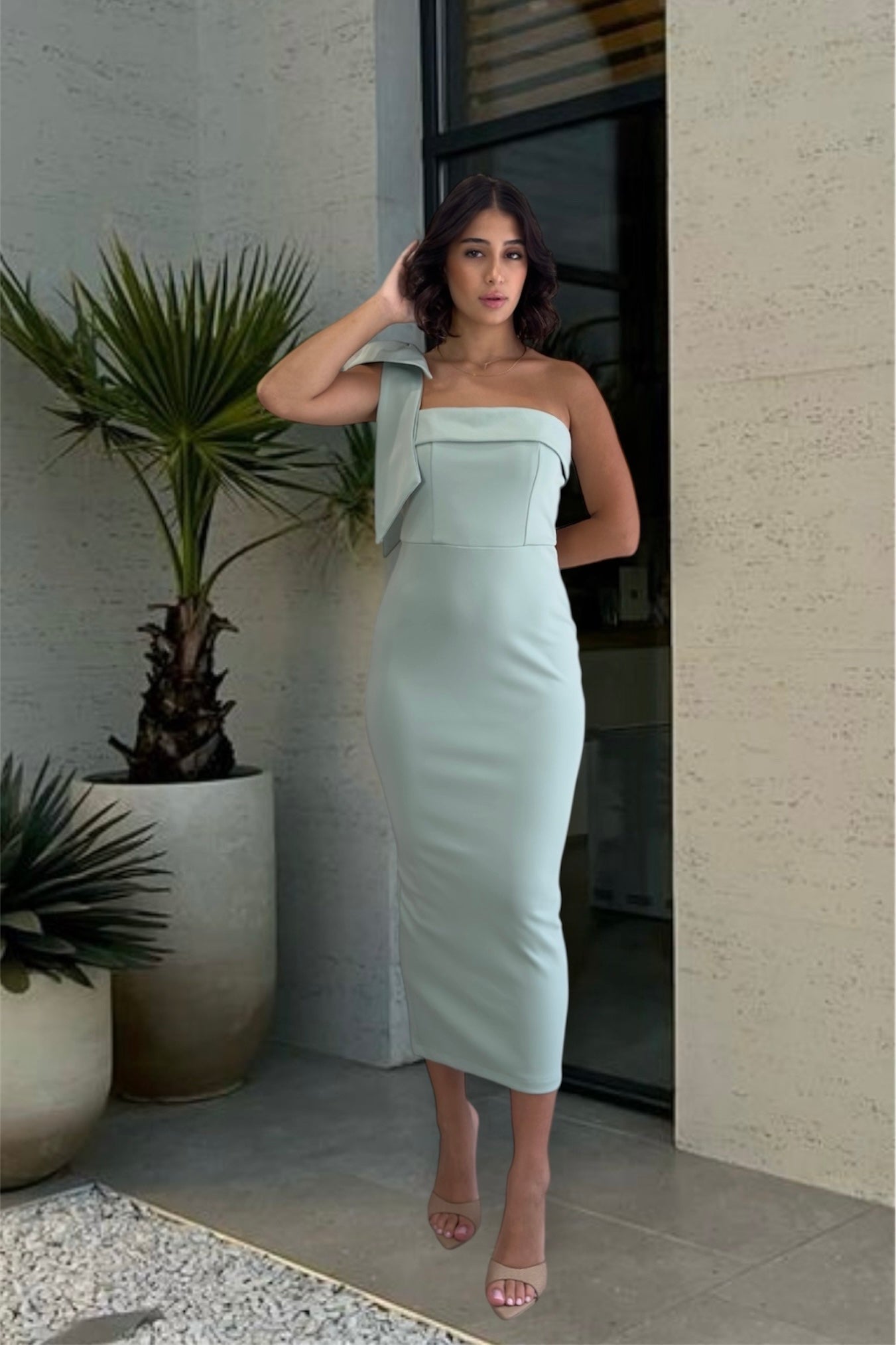 Woman in a light green strapless dress standing in front of a building entrance.
