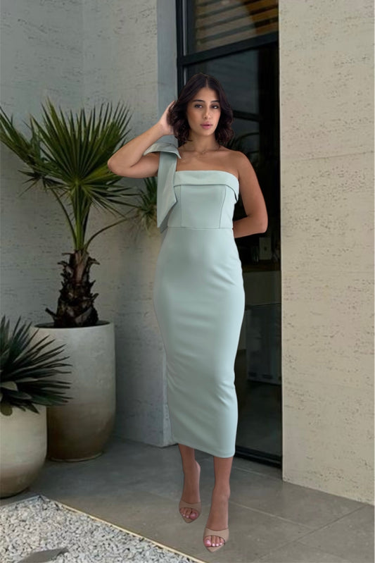 Woman in a light green strapless dress standing in front of a building entrance.