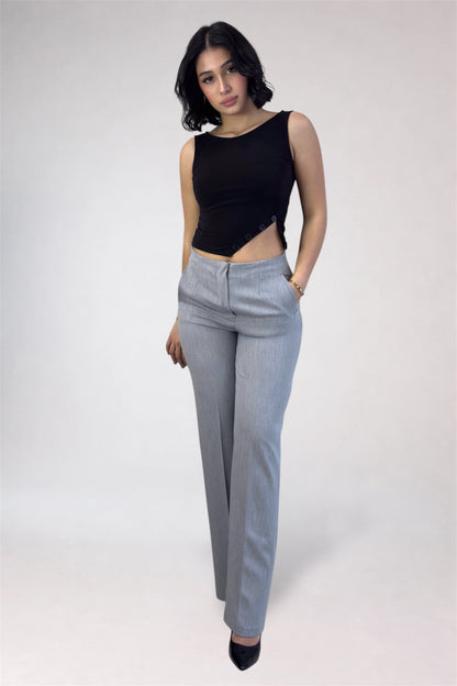 Woman wearing a black sleeveless top and gray pants on a white background