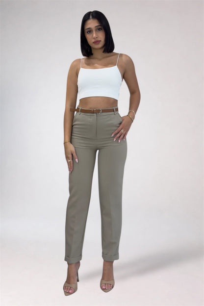 Woman wearing a white top and beige pants on a plain background