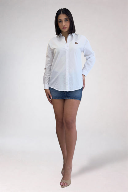 Woman wearing a white button-up shirt and denim shorts on a plain background
