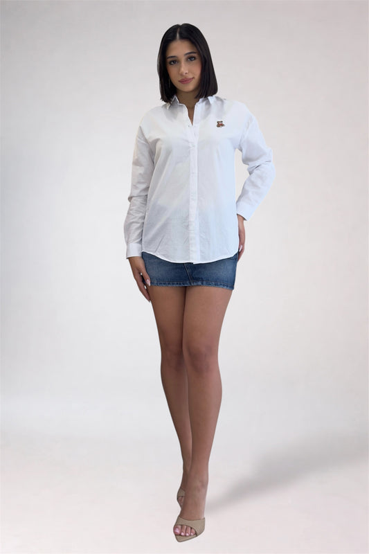 Woman wearing a white button-up shirt and denim shorts on a plain background