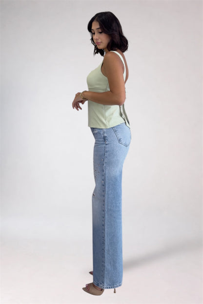 Woman wearing a light green top and blue jeans on a white background