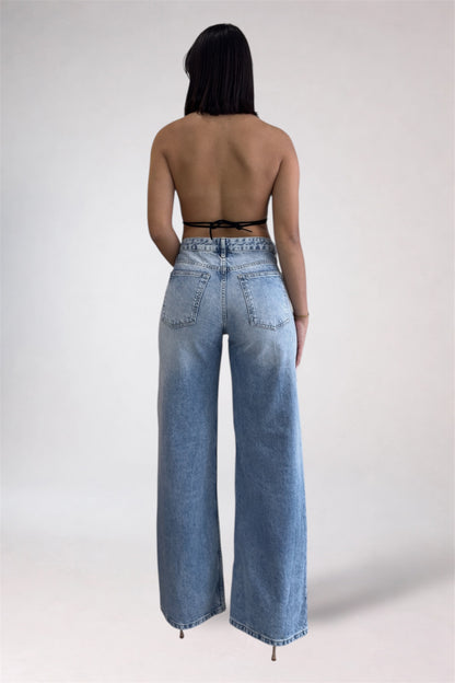 Person wearing high-waisted blue jeans with a plain background