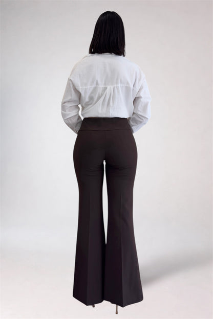 Person wearing a white shirt and brown flared pants on a plain background