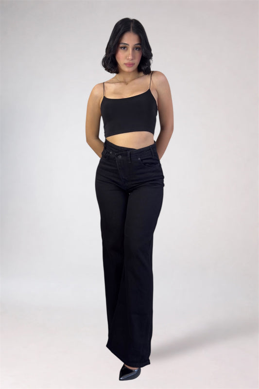 Woman wearing a black top and black high-waisted jeans on a white background