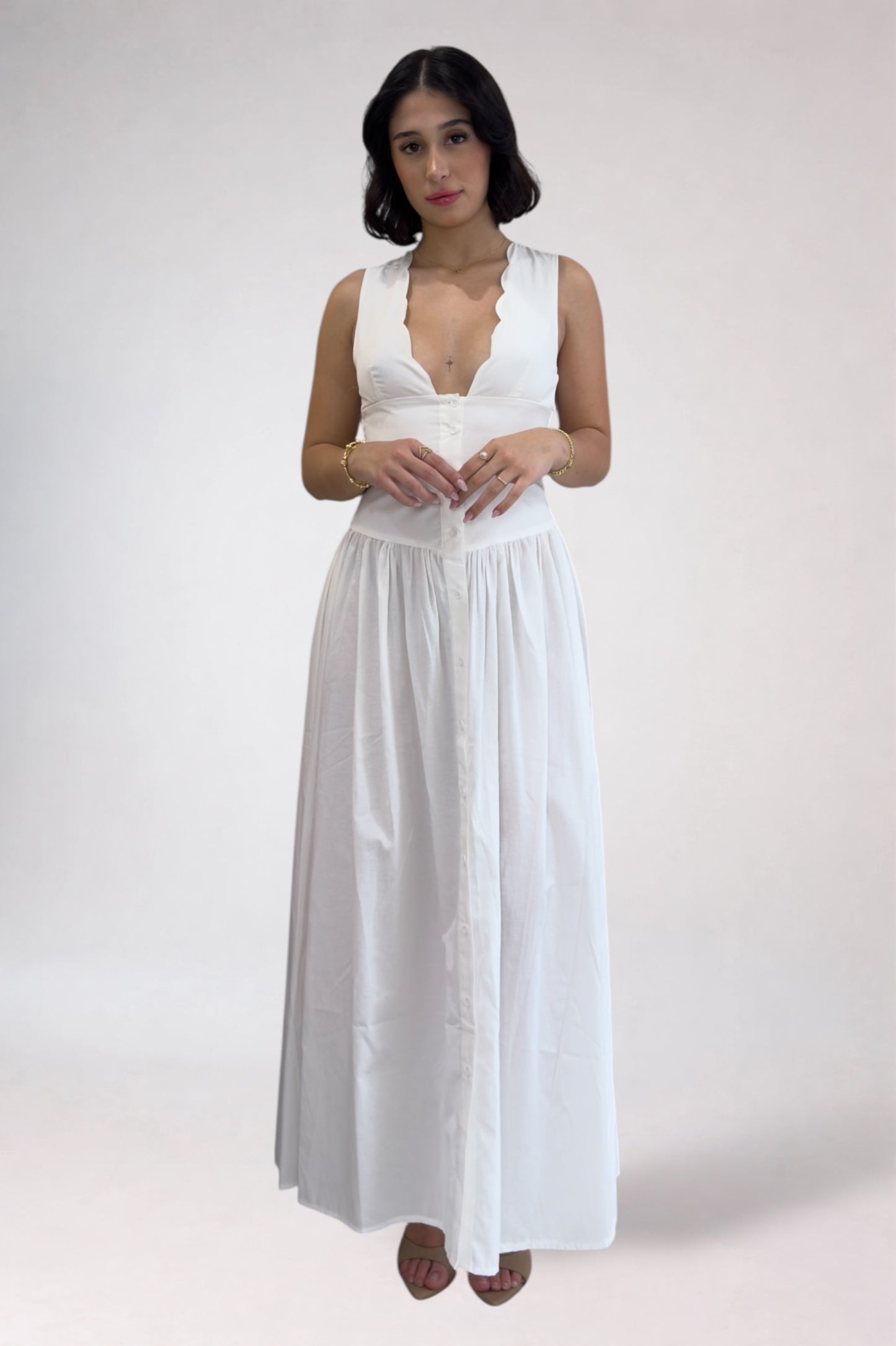 Woman wearing a white sleeveless top and long skirt against a plain background