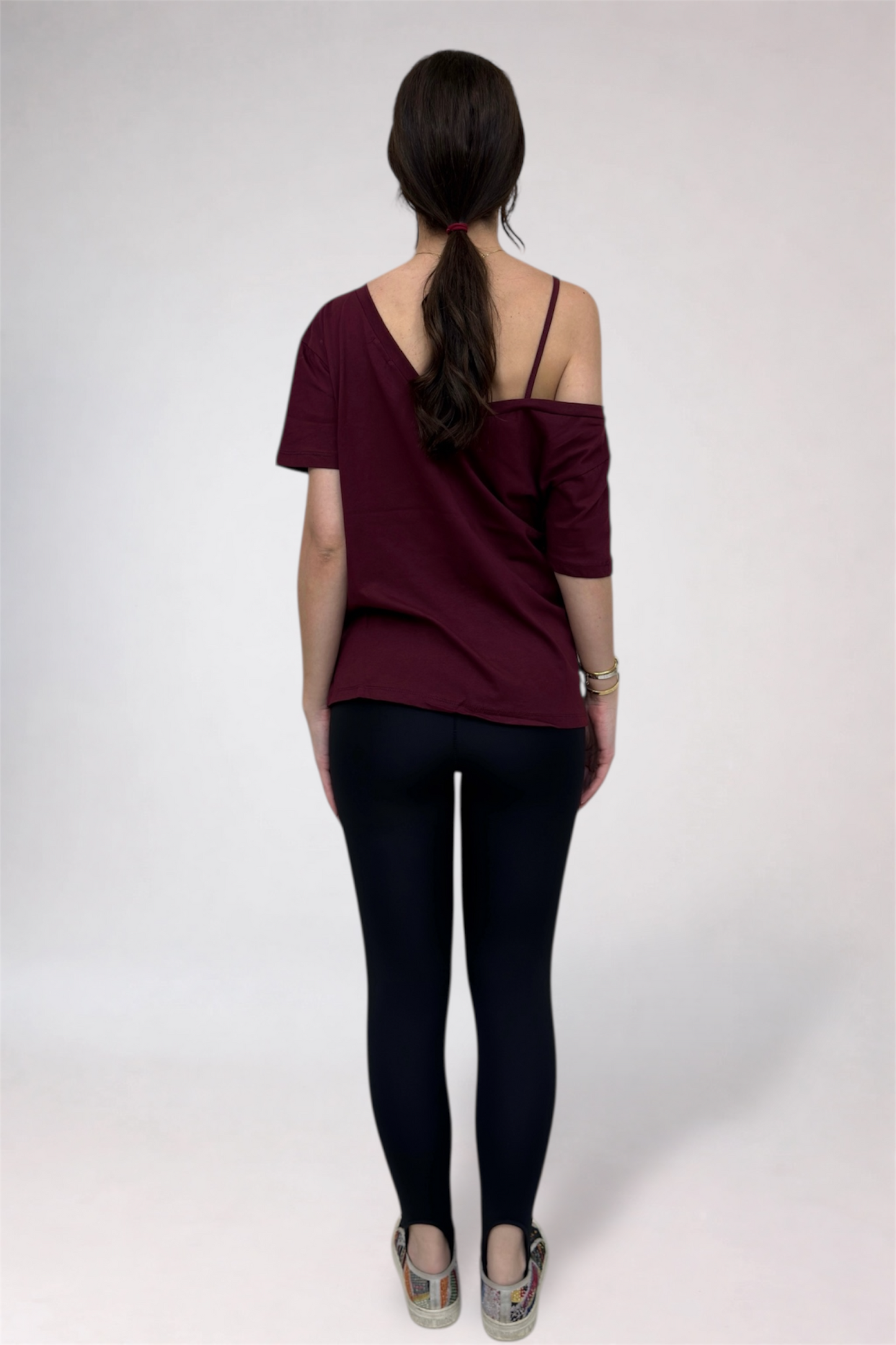 Woman wearing a burgundy top and black pants on a white background