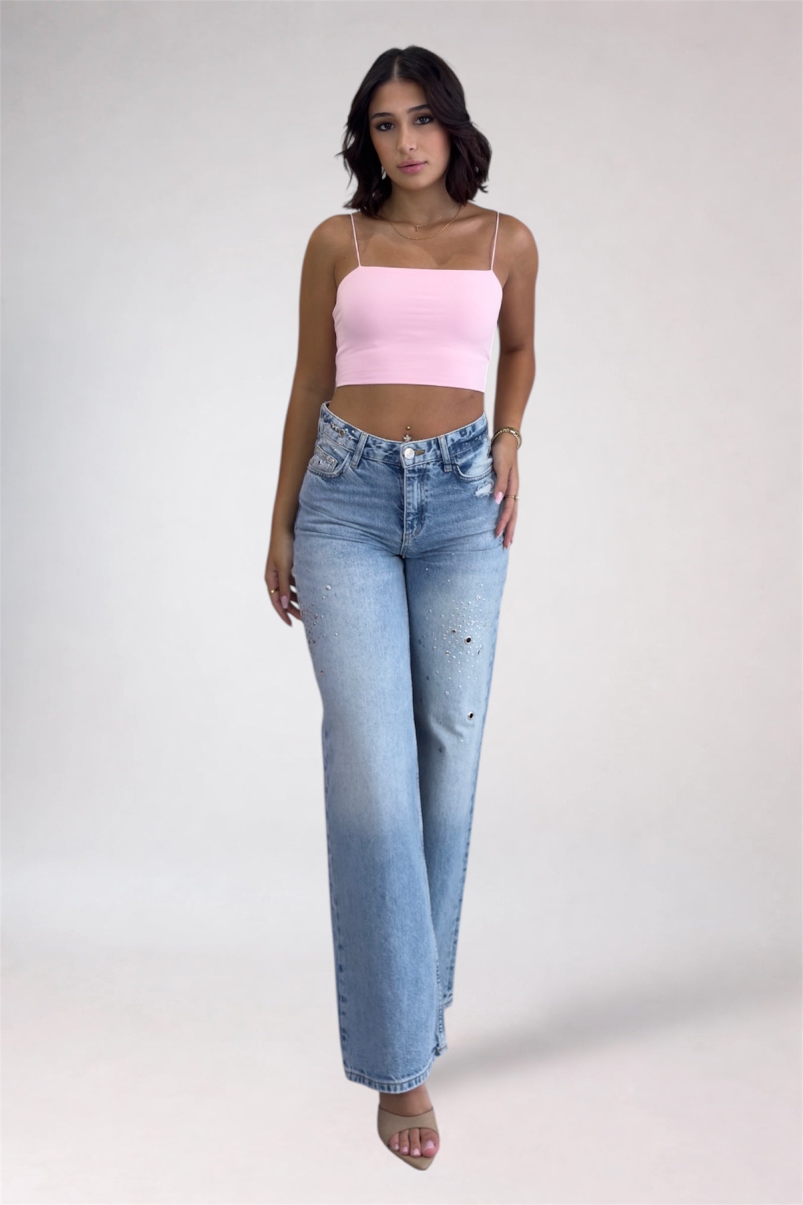 Woman wearing a pink top and light blue jeans on a white background
