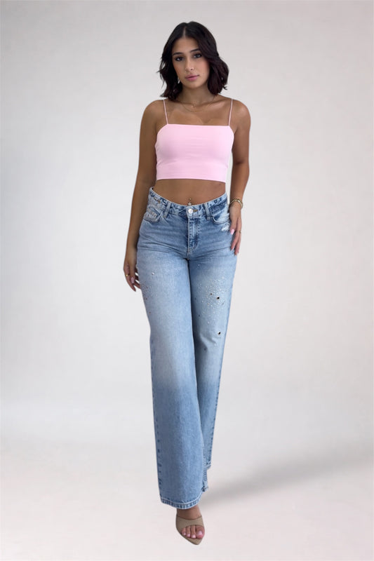 Woman wearing a pink top and light blue jeans on a white background