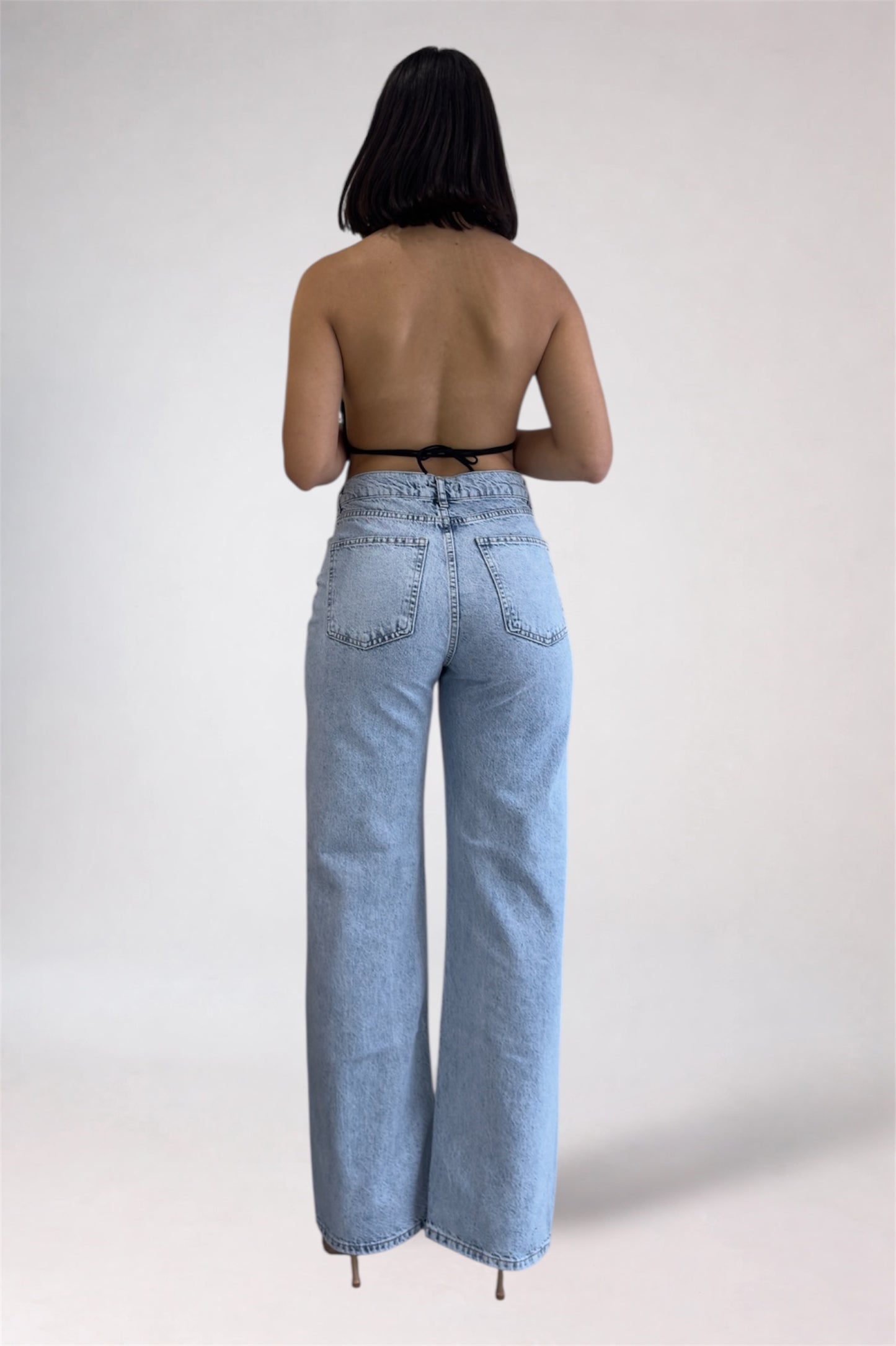 Person wearing light blue jeans on a plain background