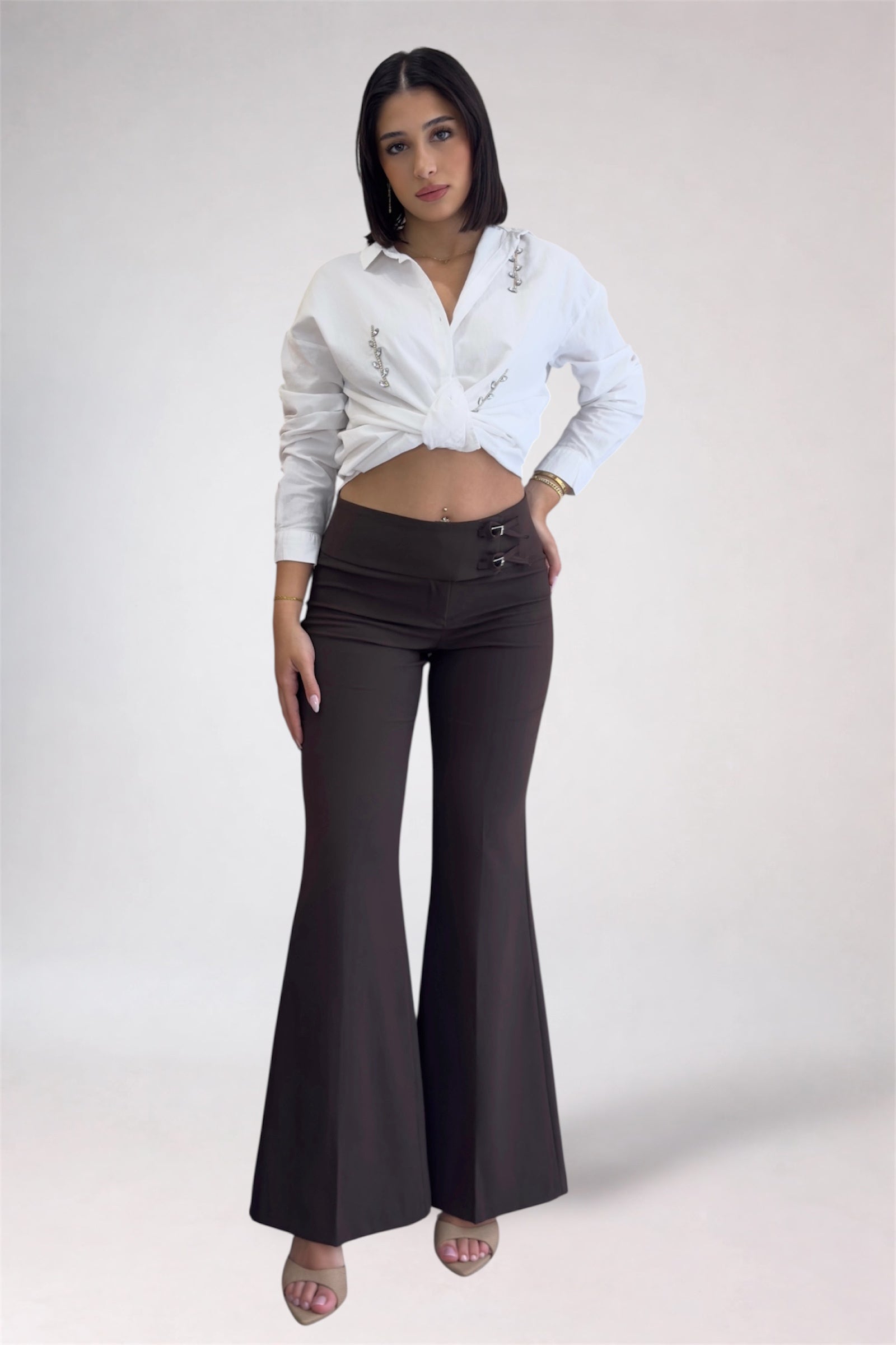 Woman wearing a white shirt and black flared pants on a plain background