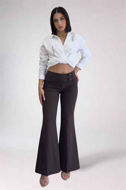 Woman wearing a white shirt and black flared pants on a plain background