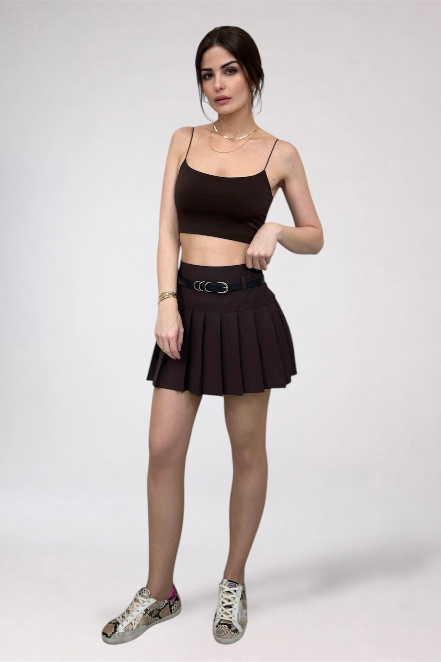 Woman wearing a black crop top and pleated skirt on a white background