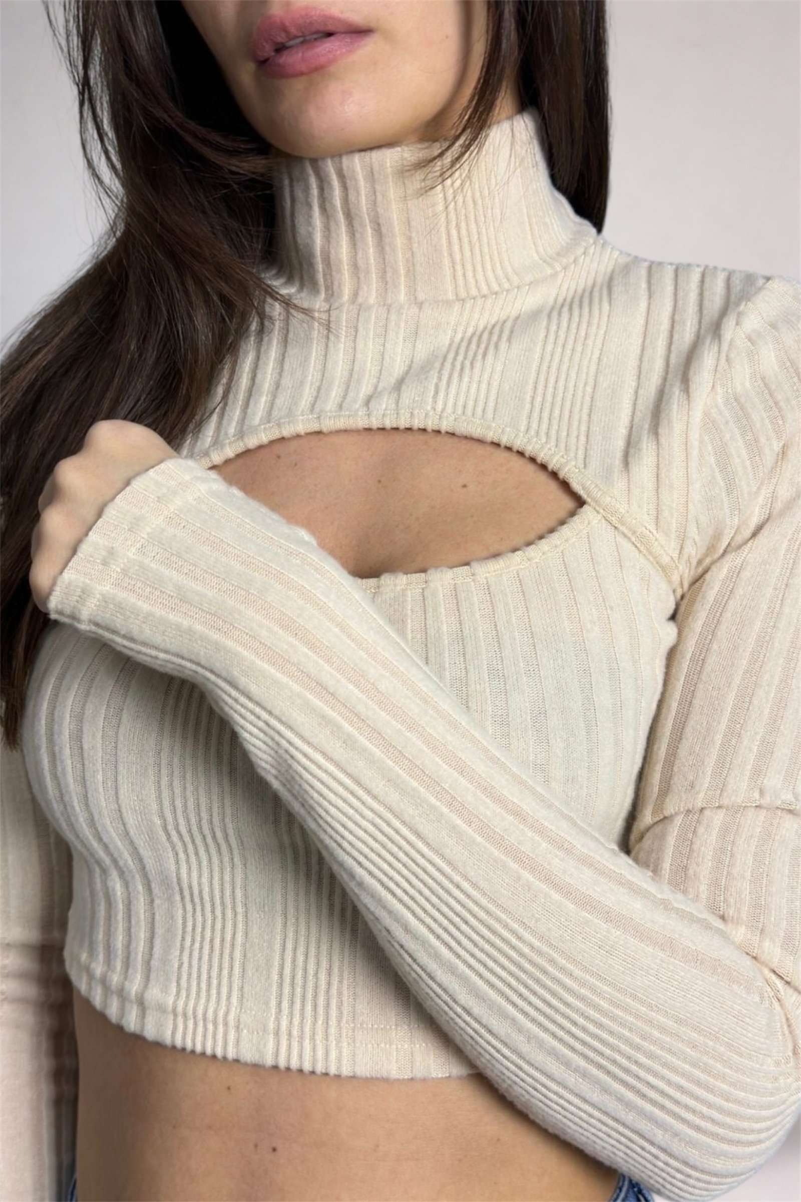 Close-up of a person wearing a ribbed turtleneck sweater with cut-out design.